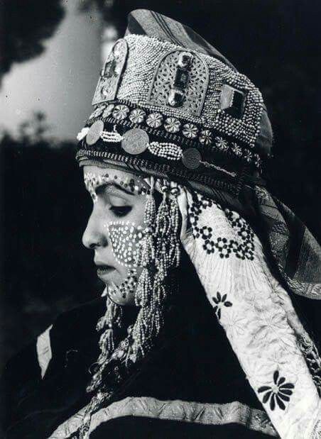 A woman wearing a Moroccan headdress in an old black and white photo.